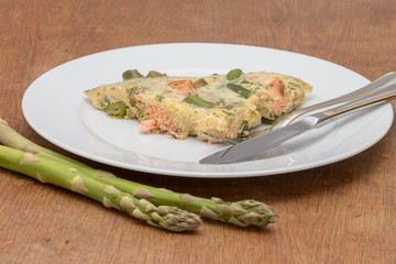 Omelette mit grünem Spargel und Lachs angerichtet auf einem weißen Teller