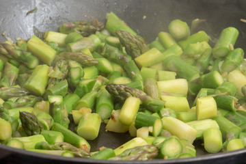 Green asparagus cutted in small pieces roasting in a pan