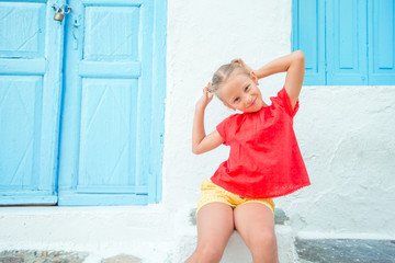 Cute girl at street of typical greek traditional village on Mykonos Island, in Greece