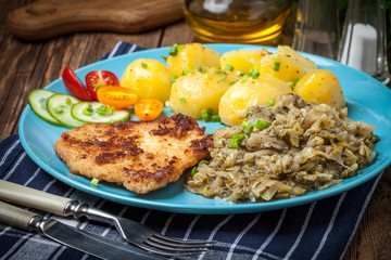 Fried pork chop, baked potatoes and fried young cabbage.