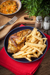 Roasted chicken with french fries on a plate.