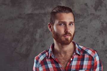 Young handsome redhead model man in a flannel shirt on a gray background.