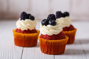 Tasty red velvet cupcakes on wooden table.