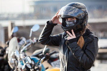 Young girl biker trying black motorcycle helmet for ride on bike