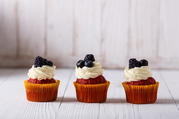 Tasty red velvet cupcakes on wooden table.