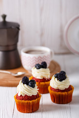 Tasty red velvet cupcakes on wooden board. Geyser coffee maker.