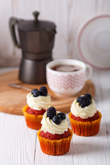 Tasty red velvet cupcakes on wooden board. Geyser coffee maker.