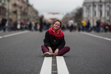 Girl sitting on the road in the middle of the street.