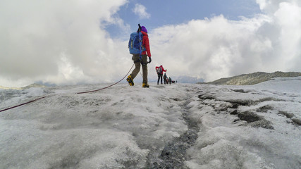 group of climbers climb the steep slopes of the snow-capped mountains on a clear day