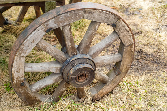 Close-up of one wheel of antique cart with three barrels for transporting goods