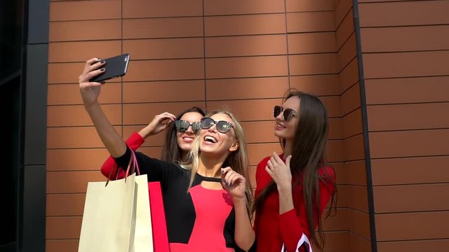 Three happy girls taking pictures and shopping. Three sophisticated female friends having fun together after enjoying a shopping trip. slow-motion