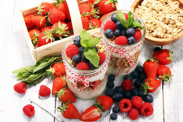 Glass jar of homemade granola with yogurt and fresh berries