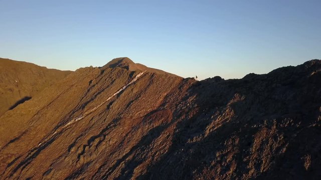 Low aerial sunrise view of Grib Goch, Snowdonia with mountain climbing man.