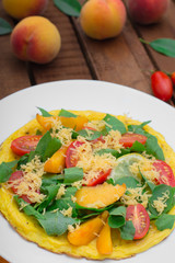 Frittata with peach, vegetables and cheese in a white plate on the rustic wooden background. Top view