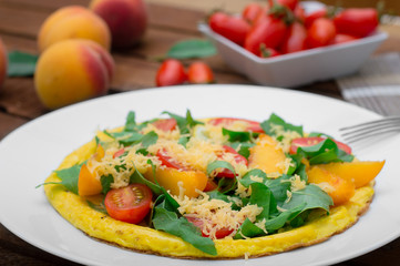 Frittata with peach, vegetables and cheese in a white plate on the rustic wooden background. Top view