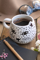 Black fragrant coffee, flowers, hat and glasses. Good morning, bright sunny colors. Women's accessories and notepad with a pen.