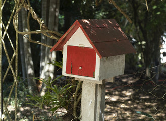 Painted wooden mail house white and red in the driveway 