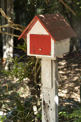 Painted wooden mail house white and red in the driveway 