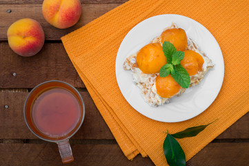Cake with diced peach, whipped cream and mint. Wooden rustic background. Top view