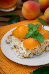 Cake with diced peach, whipped cream and mint. Wooden rustic background. Top view