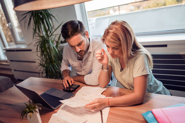 Young couple calculating bills at home