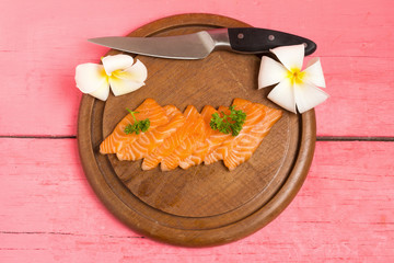 salmon sushi on cutting board with flower on wood color pink