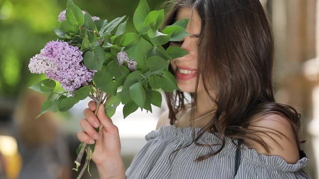 Happy woman enjoying lilac smell