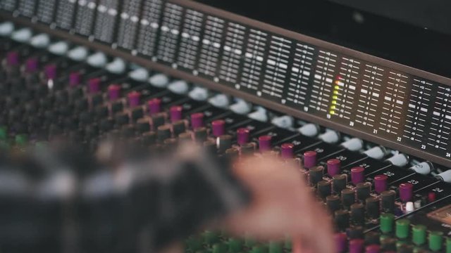 Follow Hands on Audio Board Hand Held. a hand is adjusting knobs on a recording audio board and follows hand down