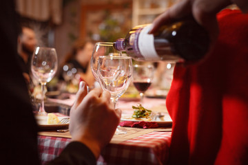 waiter pours red wine into the glasses
