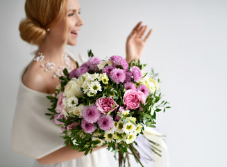 Naklejka premium Beautiful woman hold bouquet of chrysanthemum and roses flowers white and purple happy smiling on grey 
