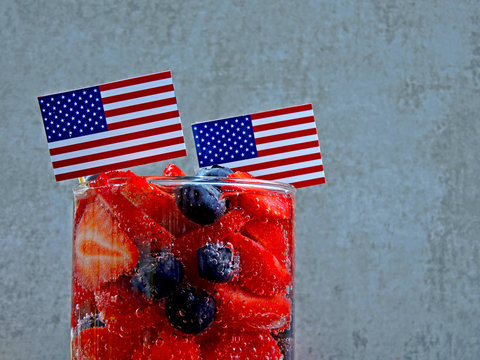 A festive lemonade with strawberries and blueberries on Independence Day. Soda in patriotic style. American flags.