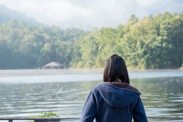 Fototapeta premium The girl watches the lake in the morning.