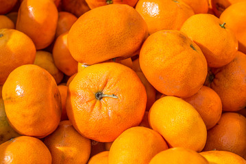 full frame close up of bright orange ripe tangerines at a farmer's market