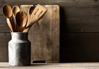Wooden kitchen cooking tools with spoons and spatula with menu board in front of rustic wooden...