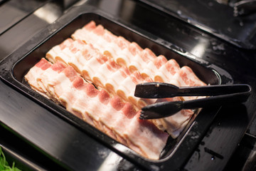 Bacon in black tray on buffet bar in restaurant.