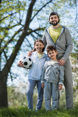 happy family with soccer ball standing in park
