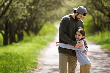 father embracing daughter on path in park