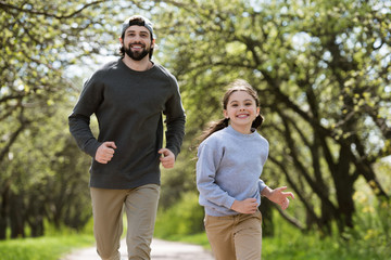 smiling father and daughter running in park