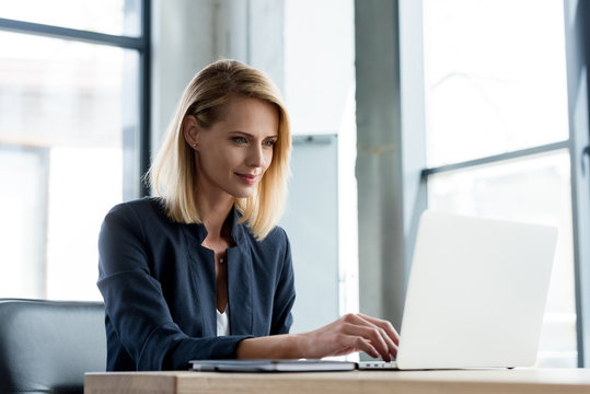 smiling professional businesswoman working with laptop in office