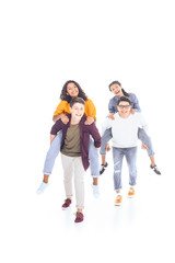Fototapeta premium happy interracial teen friends piggybacking together isolated on white