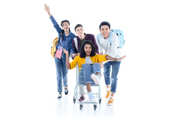 Fototapeta premium teen students riding their friend on shopping cart isolated on white