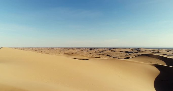 Aerial view flying over sand dunes in desert at sunset