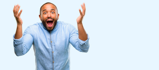 Fototapeta premium African american man with beard scared in shock, expressing panic and fear isolated over blue background