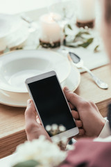 cropped shot of groom using smartphone at served rustic table