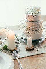 close up view of stylish table setting with candles and wedding cake for rustic wedding