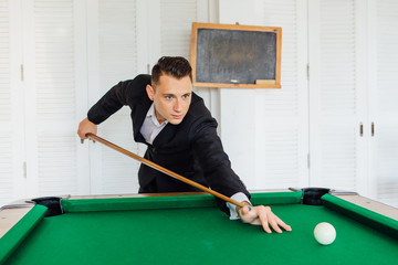 Fototapeta premium Young handsome man playing billiard game alone