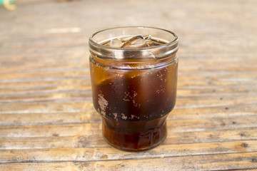Cola with ice cubes in glass on bamboo table