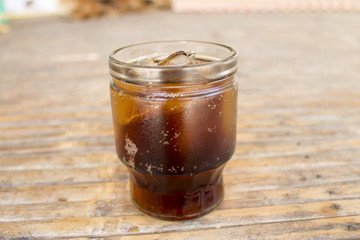 Cola with ice cubes in glass on bamboo table
