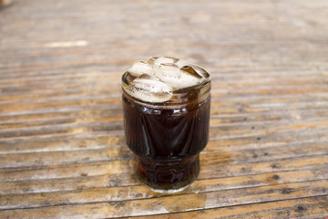 Cola with ice cubes in glass on bamboo table