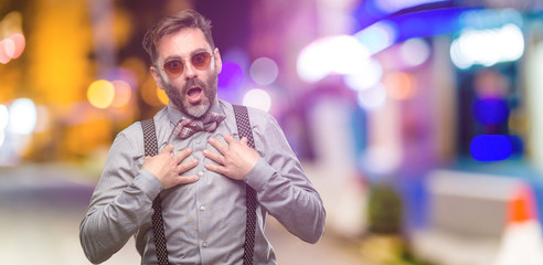 Middle age man, with beard and bow tie happy and surprised cheering expressing wow gesture at night club